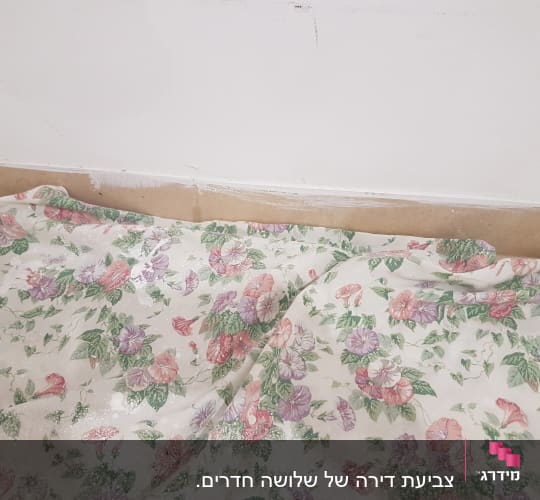 קיר צבוע עם כתמי צבע ויריעת בד פרחונית